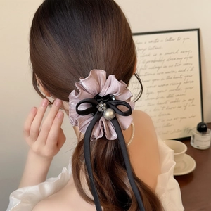 Detail showing elegant lavender satin hair clip with black ribbon bow and pearl flower
