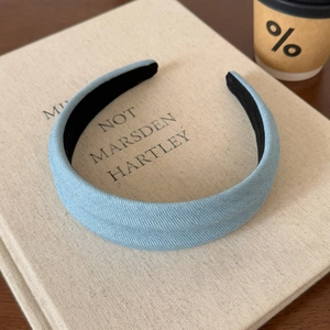 Detailed texture of a wide vintage light blue denim headband on a minimalist book