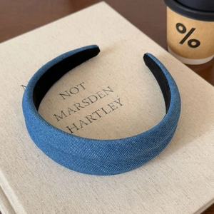 Detail of blue denim headband on beige books with a lifestyle aesthetic setting