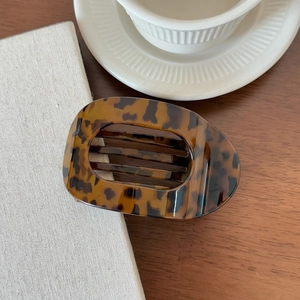 Molla per capelli tartarugata con design ovale traforato su tavolo in legno
