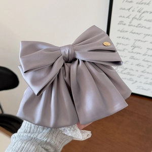 Détail d'une grande pince à cheveux noeud en satin violet avec bouton doré de luxe