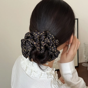 French vintage black scrunchie with yellow polka dots on hair bun in a cozy room