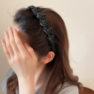 Elegant black woven headband with beaded details worn by a model in a profile view