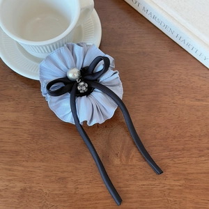 Detail of blue ruffled hair scrunchie with black ribbon bow and pearl charm