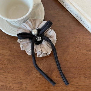 Close-up of elegant ruffled fabric hair clip with a large pearl and sparkling rhinestone accents