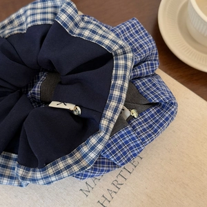 Detail of blue scrunchie with check pattern, woven label, and gold heart charm