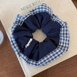 Detail of blue plaid scrunchie with a gold heart pendant on a vintage book