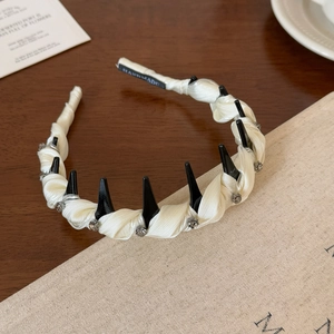 Dettaglio del cerchietto in raso crema fatto a mano con borchie punk nere e strass lucidi