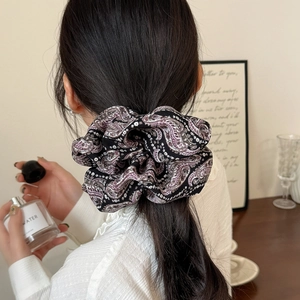 Detail of elegant large paisley print scrunchie styled on a ponytail in a soft home setting
