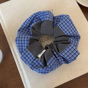 Close-up of blue plaid scrunchie with a gold heart pendant on a vintage book
