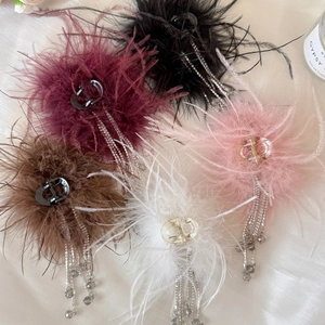 Vue détaillée de pinces à cheveux en plumes avec pompons perlés en cinq couleurs variées