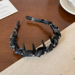 Dettaglio ravvicinato di un cerchietto punk nero con punte e strass scintillanti
