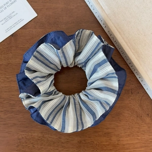 Detail of blue and white striped scrunchie with layered fabric texture on wood surface