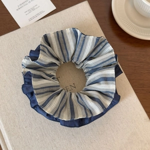 Detail of blue and white striped scrunchie with dark blue ruffled edges on a book