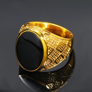 Macro detail of men's gold ring showing black oval stone and side relief texture