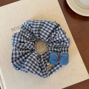 Détail d'un chouchou à carreaux bleus avec nœud en denim et bouton en bois rond