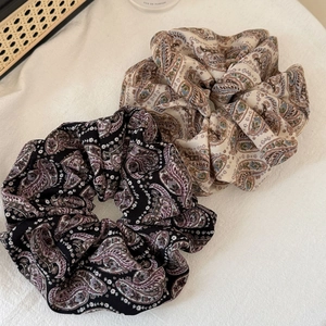 Close-up of large paisley print fabric scrunchies in beige and black elegant patterns