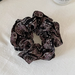 Detail of elegant paisley floral fabric scrunchie with vintage pleated texture