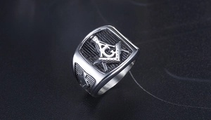 Detalle macro de anillo masónico plateado con símbolo de escuadra y compás grabado