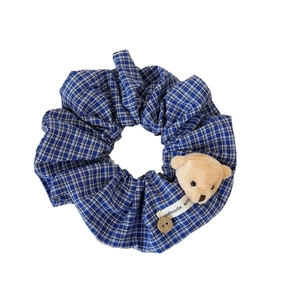 Chouchou à carreaux bleus avec tête d'ours en peluche et bouton en bois sur fond blanc