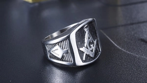 Primer plano de anillo masónico vintage plateado con compás escuadra y símbolo de la G