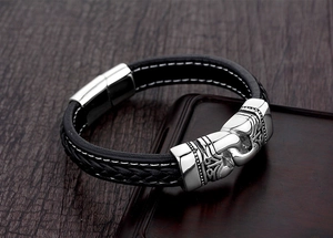 Detail of black braided leather bracelet with vintage engraved stainless steel clasp