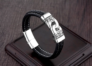 Close-up of woven black leather men's bracelet with vintage engraved metal clasp