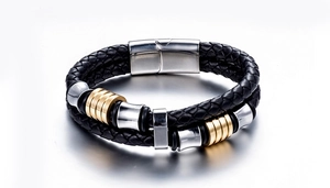 Detail of double-layer black braided leather bracelet with gold and silver metal charms