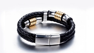 Close-up of double-layer braided black leather bracelet with gold and silver metal charms