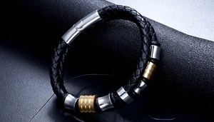 Detail of black woven leather bracelet with polished silver and gold metal cylinder beads