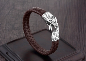 Close-up of brown braided leather bracelet with a detailed silver metal dragon head clasp
