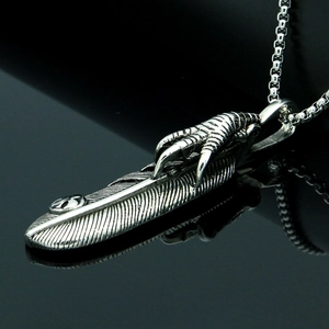 Macro shot of vintage silver eagle claw and feather pendant with intricate metal textures