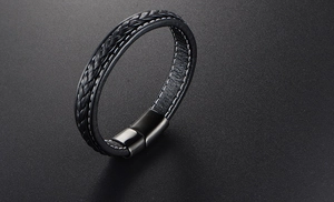 Detail of black woven leather men's bracelet with white stitching and metal magnetic clasp