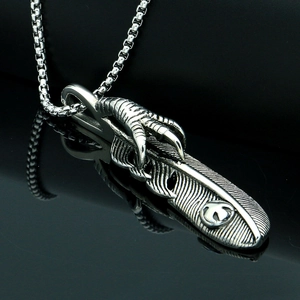 Detailed macro view of vintage titanium steel eagle claw and feather pendant on box chain