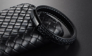 Close-up of woven black leather bracelet with white stitching and matte magnetic clasp