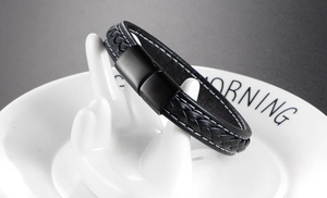 Close-up of black braided leather bracelet with matte metal magnetic clasp on white stand