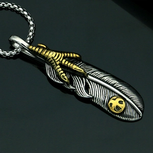Macro detail of bicolour feather pendant with golden eagle claw on silver chain