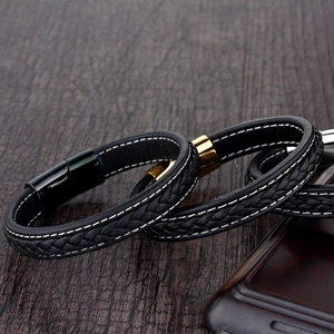 Men's woven black leather bracelet with magnetic metal clasp on dark wood surface