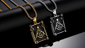 Macro detail of gold and silver masonic pendants with square, compass, and G letter