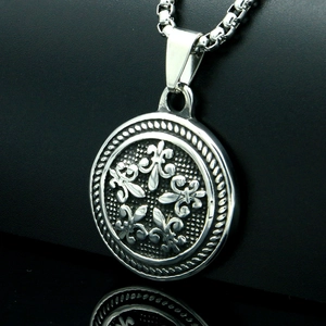 Macro shot of silver-tone stainless steel round pendant with embossed fleur-de-lis motif