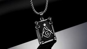 Macro detail of gothic Freemasonry pendant with G symbol and skull carvings on steel