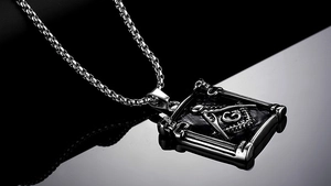 Macro detail of men's Masonic pendant with square and compass G symbol in retro silver