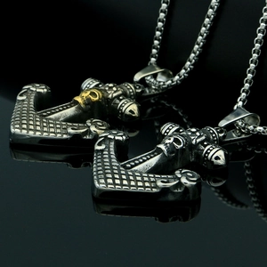 Macro detail of gothic anchor and skull pendant with polished steel bead chain