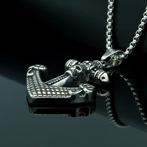 Macro detail of retro anchor pendant with skull carving on polished black mirror surface