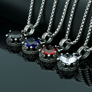 Macro detail of crown pendants with colorful gemstones on a black reflective surface