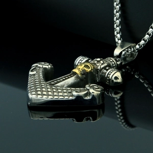 Close-up of anchor pendant with gold skull relief and vintage silver filigree details