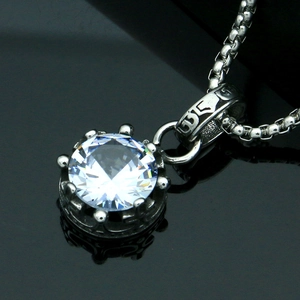 Macro shot of silver crown pendant with clear round zircon on a black reflective surface