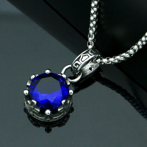 Detailed close-up of crown setting with round blue faceted gemstone on silver box chain