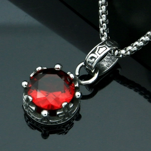 Macro shot of crown setting pendant with a faceted red gemstone on silver box chain