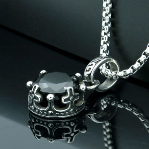 Macro shot of gothic crown pendant with black gemstone and cross details on mirror